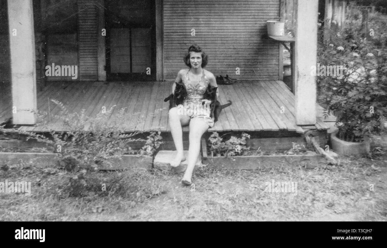 Ein junges Mädchen spielt mit ihren zwei schwarze Katzen auf dem Stoop von der Veranda Ihrer rustikalen Bauernhaus in ländlichen Greene County, Tennessee sitzen. Stockfoto