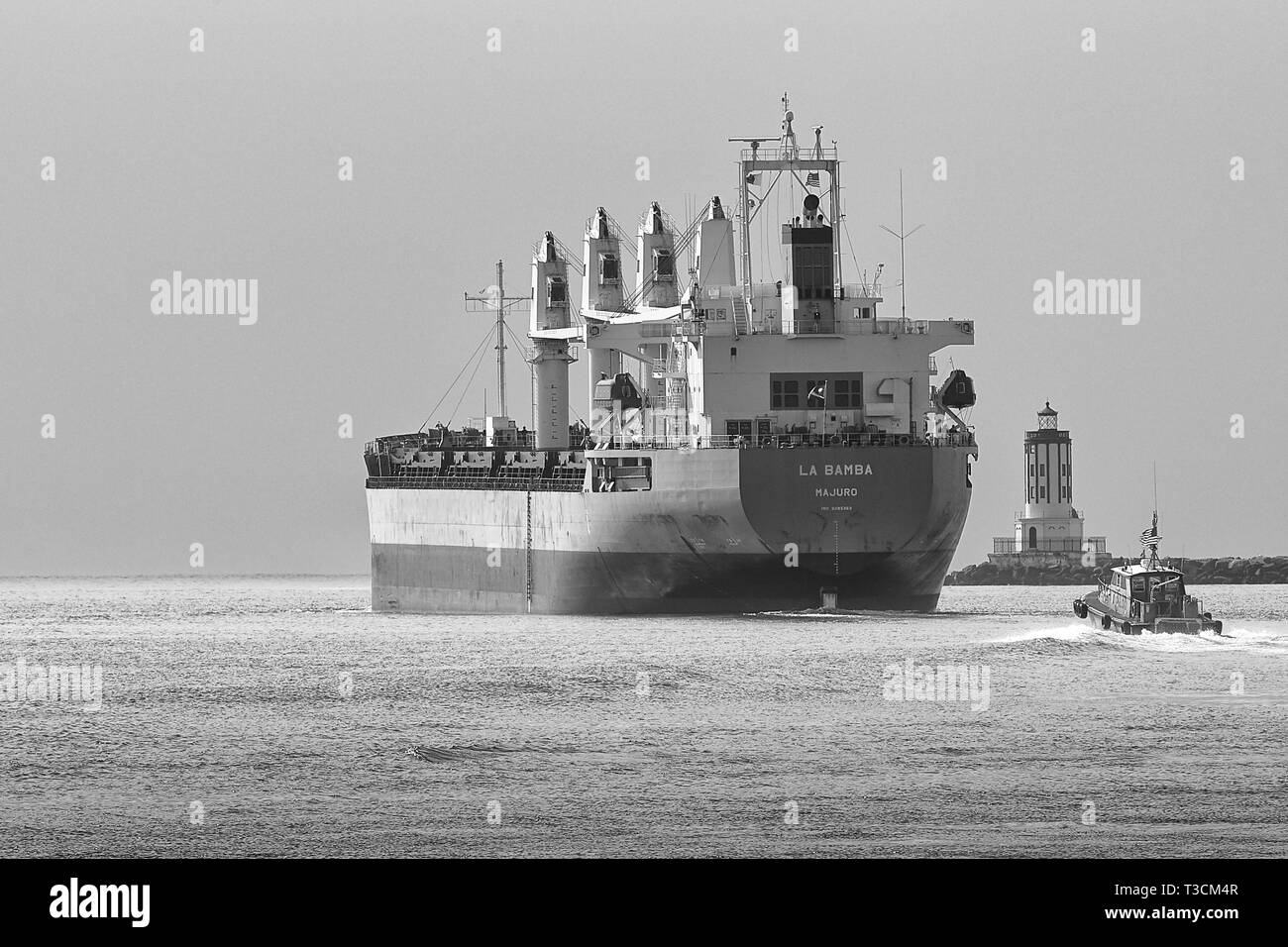 Ein Pilot-Boot folgt der Bulk Carrier, LA BAMBA und verlässt den Hafen von Los Angeles, Kalifornien, USA. Die Los Angeles Harbor Light Auf Der Rechten Seite. Stockfoto