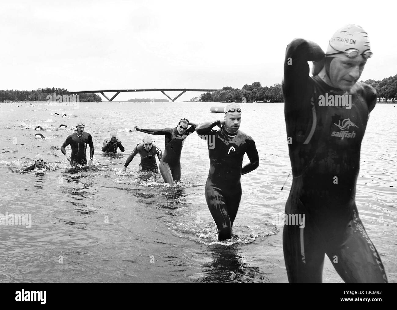 MOTALA 20140628 16 Grad im Wasser, bunten Badekappen und einen unvergesslichen Publikum. 'Vätterntriathlon' läuft. Bild: Triathleten auf dem Weg bis zum See Vättern, Motala Bridge im Hintergrund. Bild Jeppe Gustafsson Stockfoto