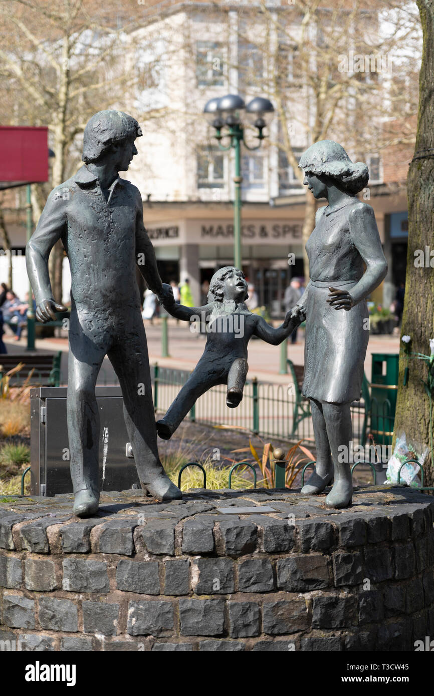 Ein Familienausflug - eine Bronzeskulptur von zwei Eltern, die die Hände eines Kindes halten, von John Ravera, errichtet auf dem Mell Square, Solihull, England Stockfoto