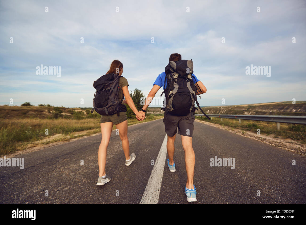 Reisende mit Rucksäcken weiter auf der Straße in der Natur Stockfoto