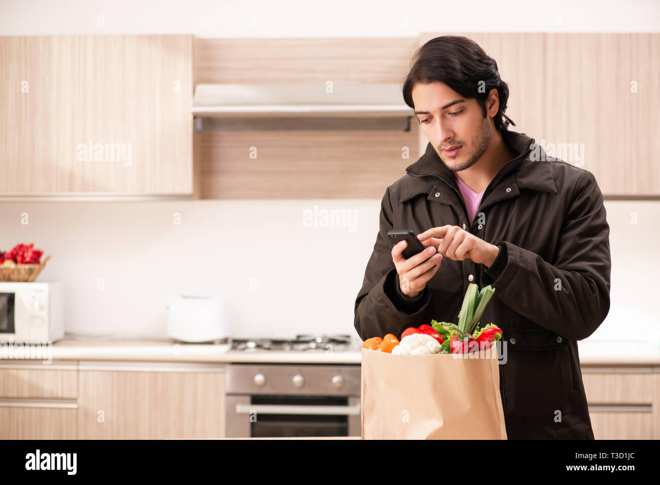 Junger stattlicher Mann mit Gemüse in der Küche Stockfoto