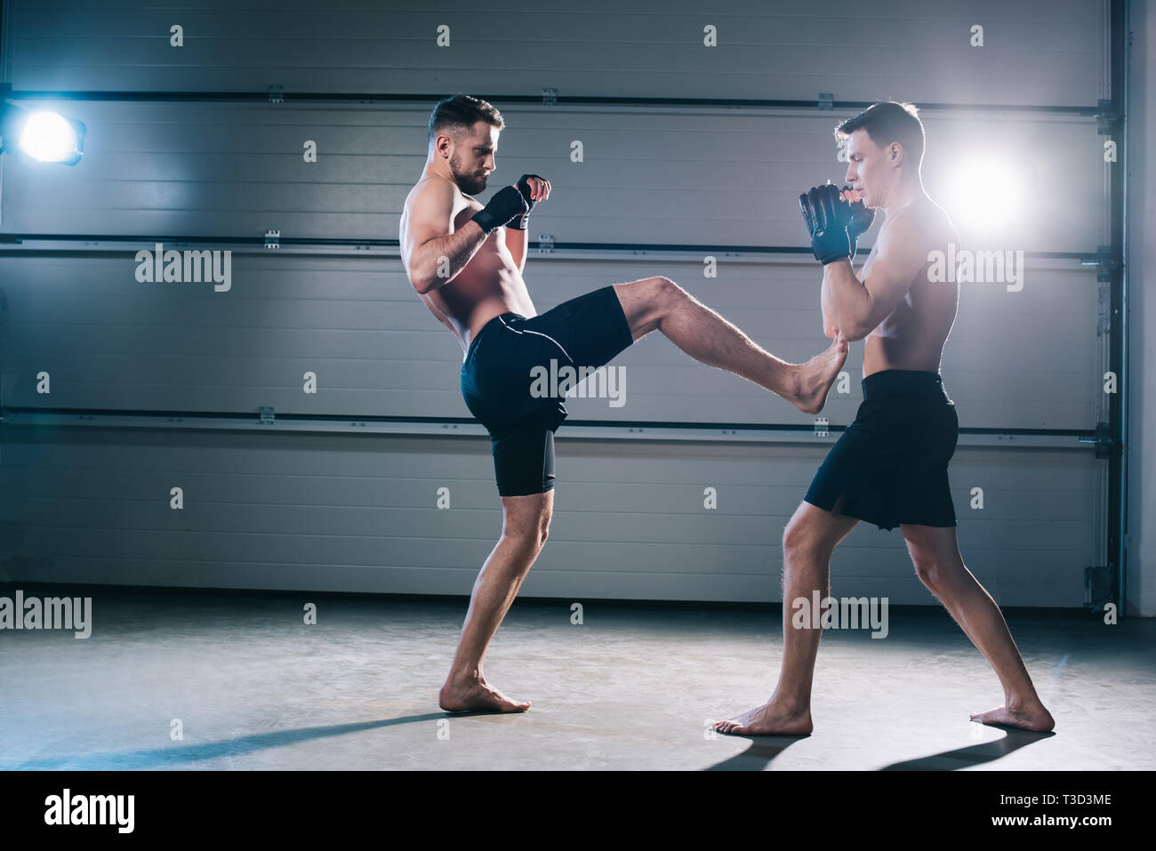 Seitenansicht von Muskel barfuß MMA-Kämpfer treten Gegner mit Bein Stockfoto
