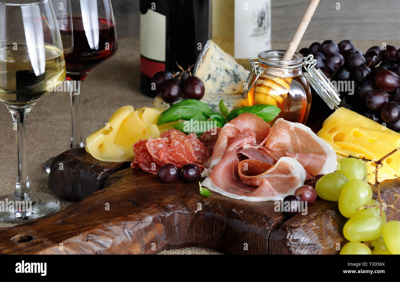 Antipasto catering Plattenteller mit ruckartiger Speck, Schinken, Salami, Käse und Trauben auf einem hölzernen Hintergrund Stockfoto