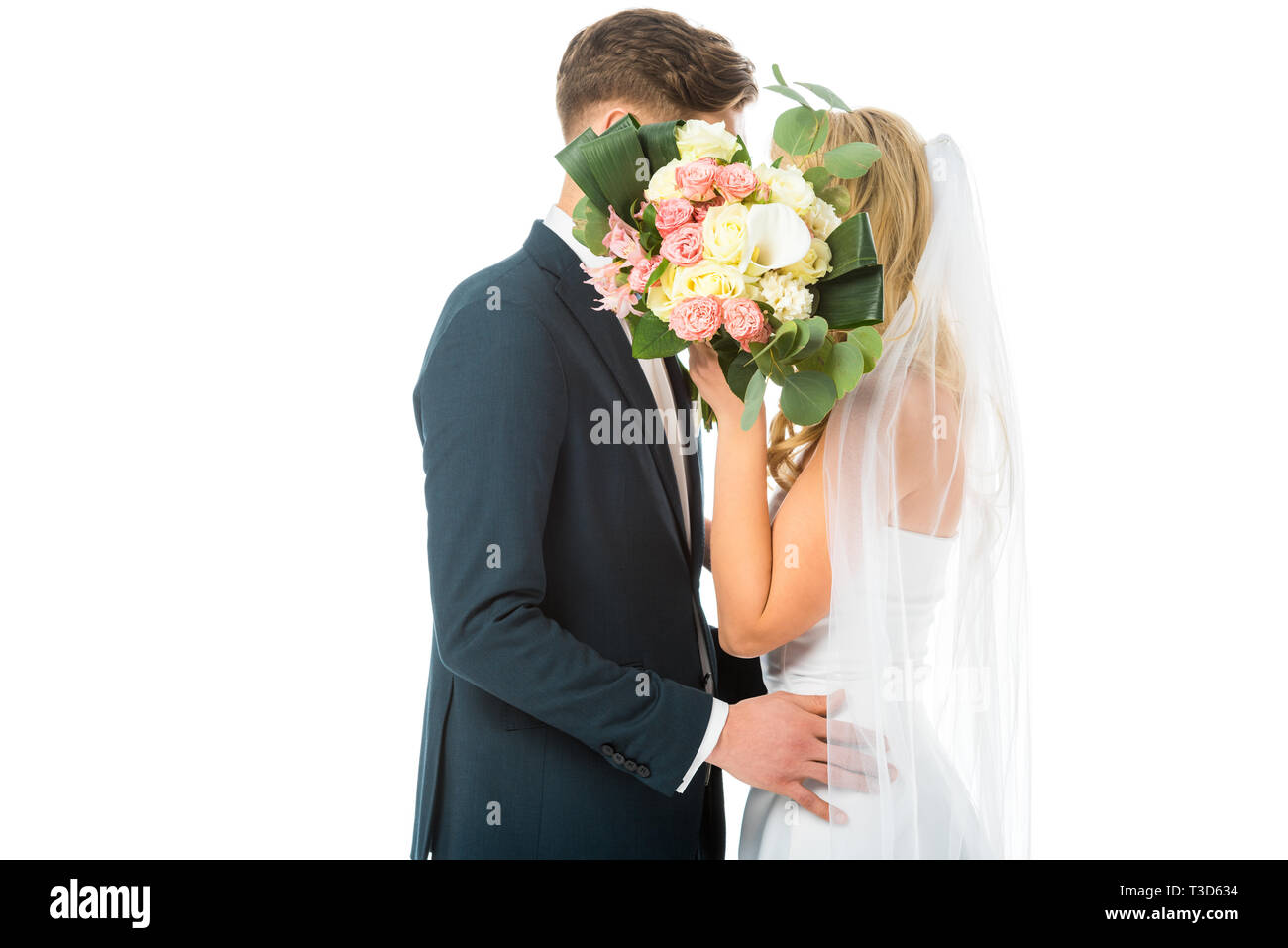 Braut und Bräutigam umarmen beim Verstecken Gesichter hinter wedding bouquet isoliert auf weißem Stockfoto