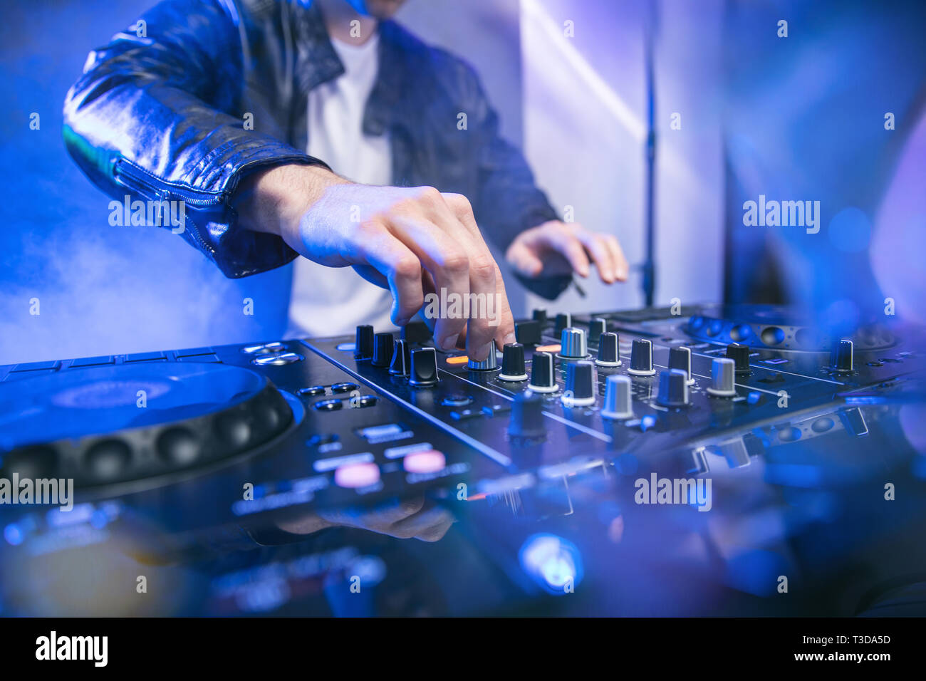 Dj-mixing bei Party Festival mit blauen Lichtern und Rauch im Hintergrund - sommerliche Nachtleben Blick auf disco club im Inneren. Fokus auf der Hand Stockfoto