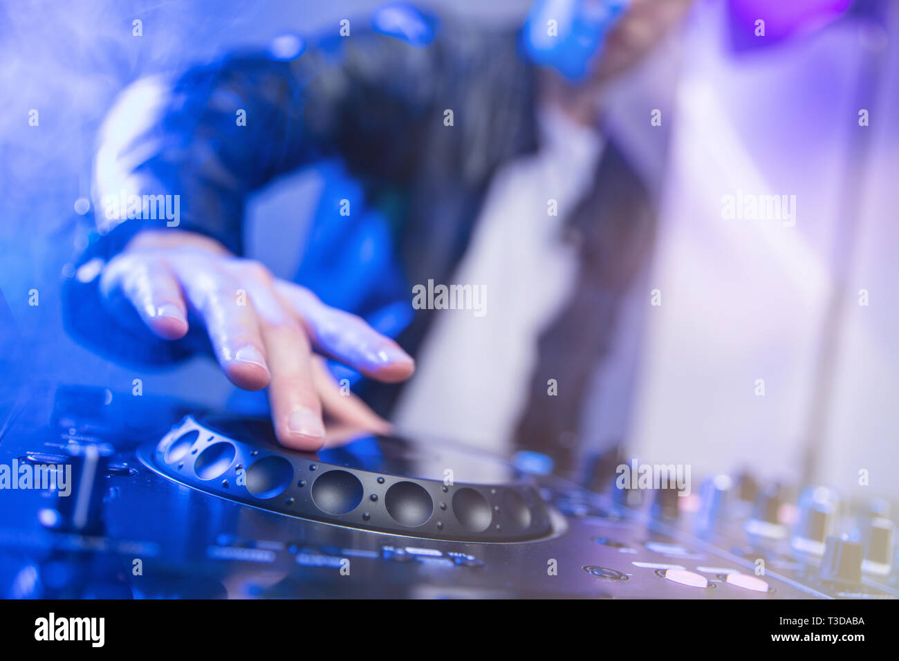Dj-mixing bei Party Festival mit blauen Licht und Rauch im Hintergrund - sommerliche Nachtleben Blick auf disco club im Inneren. Fokus auf der Hand Stockfoto