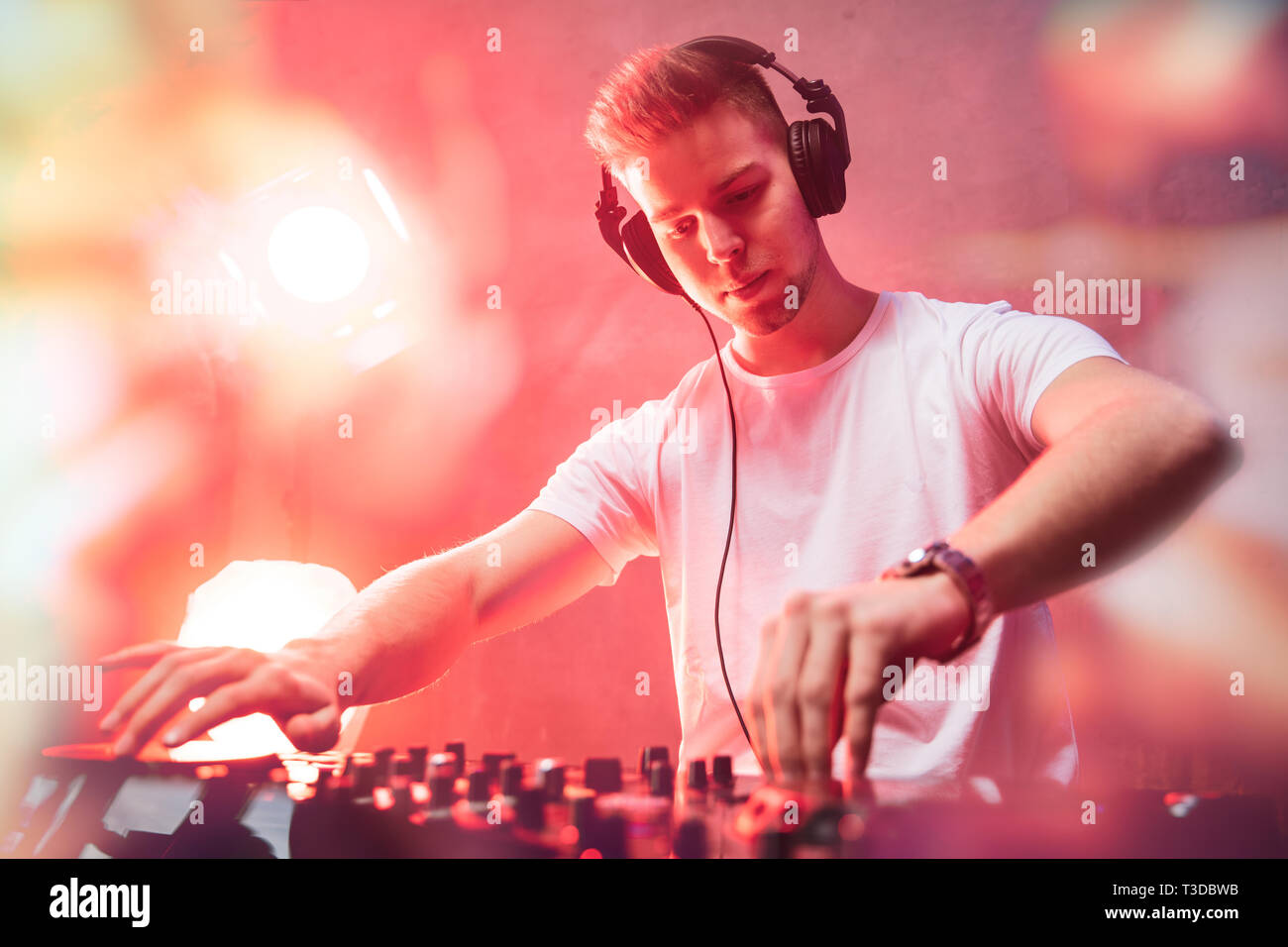 Dj-mixing bei Party Festival mit rotem Licht und Rauch im Hintergrund - sommerliche Nachtleben Blick auf disco club im Inneren. Fokus auf das Gesicht Stockfoto