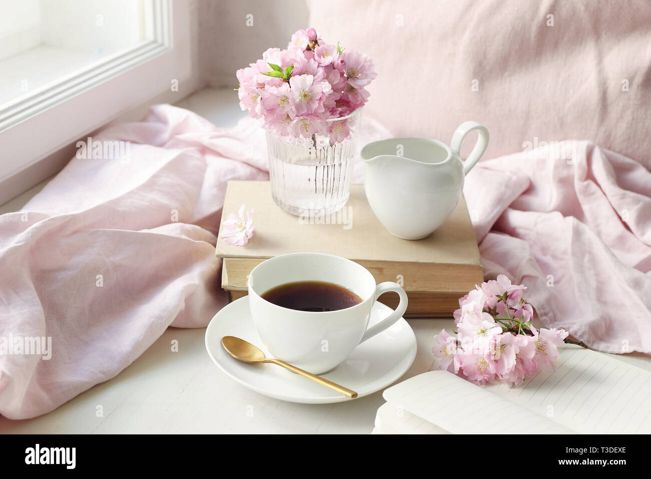 Der Frühling noch leben Szene. Tasse Kaffee, alte Bücher und Milch Krug. Vintage feminin Foto, blumige Komposition mit rosa Sakura, cherry tree bl Stockfoto