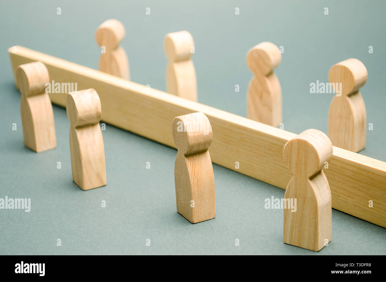 Holzfiguren von Menschen sind durch eine Barriere getrennt. Soziale Klassen. Der Wettbewerb zwischen den Teams. Das Konzept von Missverständnissen. Eine Schranke in Bezug Stockfoto