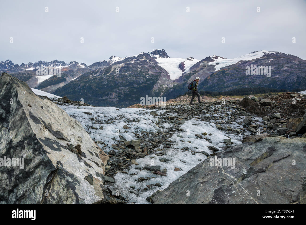 Junge Frau wandern auf einem Gletscher im Hinterland von British Columbia. Im Hintergrund sind viele hohe Berge mit hängenden Gletschern und Rocky Stockfoto