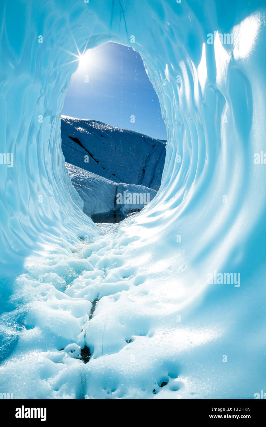 In der Alaskan Backountry auf der Matanuska Gletscher, die Sonne scheint durch die Öffnung eines massiven Eishöhle. Die Deep Blue Ice der Höhle/ Stockfoto