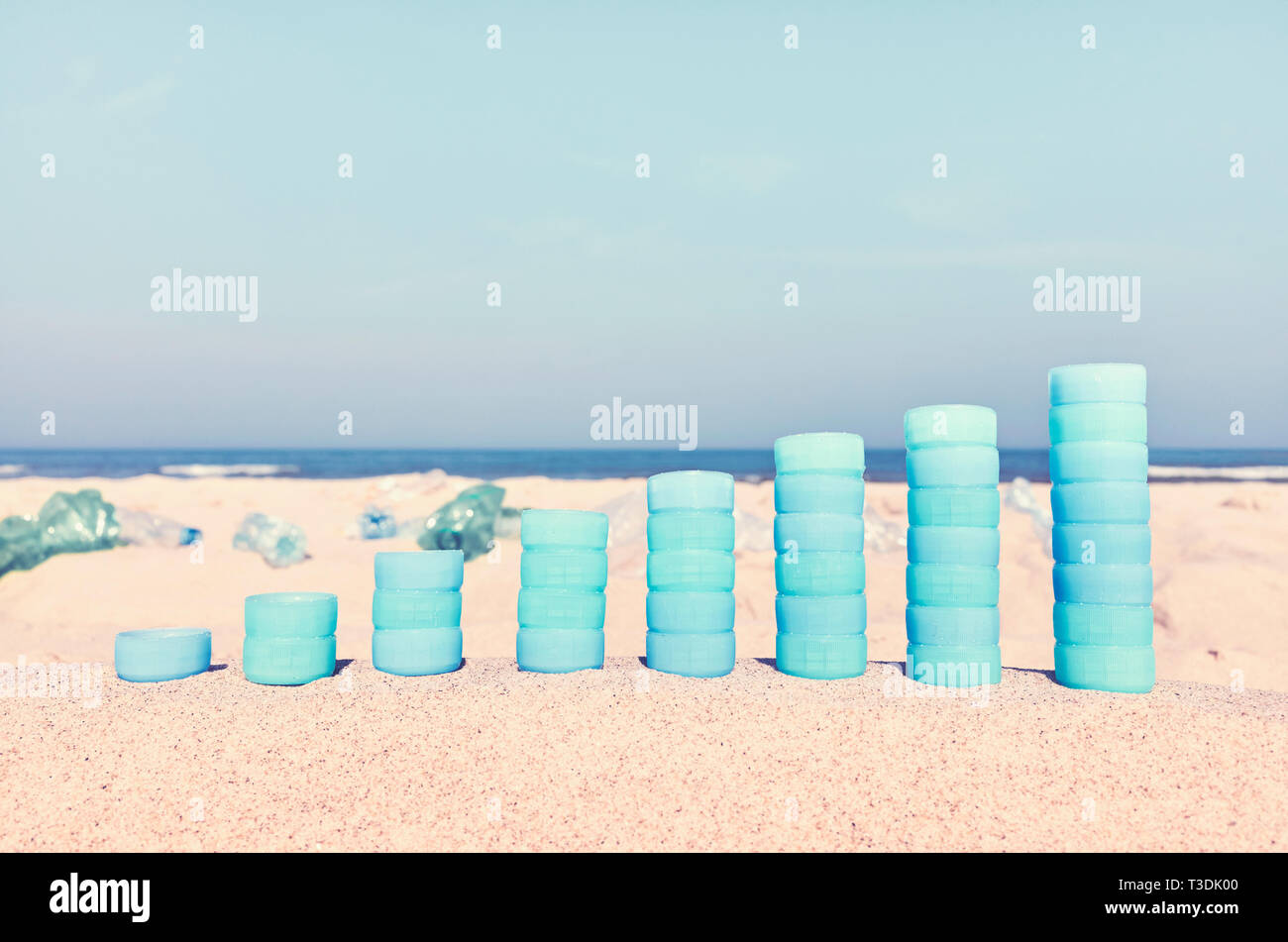 Diagramm der Plastikflaschen Caps auf Sand zeigt die Zunahme der Verwendung von Kunststoff, Farbe getonte Bild, selektive konzentrieren. Stockfoto