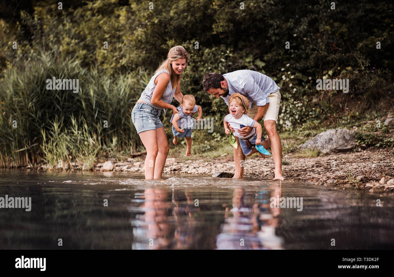 Eine junge Familie mit 2 Kleinkind Kinder draußen am Fluss im Sommer. Stockfoto