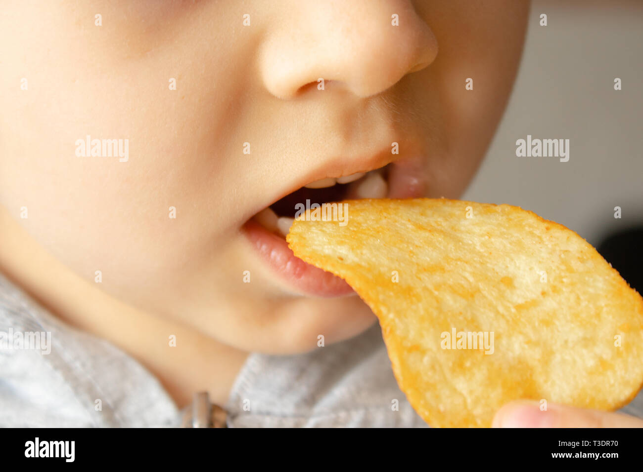 Baby essen Chips. Close-up. Das Kind hält die Chips. Junk Food. Stockfoto