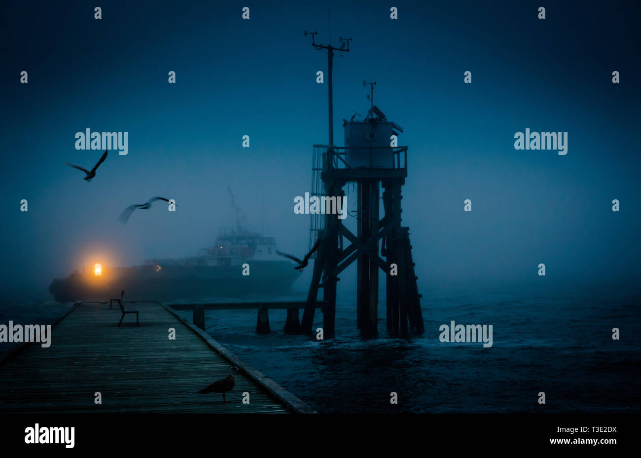 Ein Boot übergibt einen Wharf und ein Wetter Turm durch die NOAA National Data Buoy Center in​ Dauphin Island, Alabama betrieben. Stockfoto