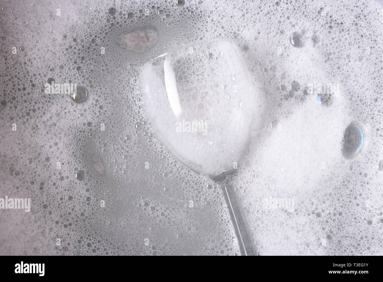 Overhead shot eine Abwaschschüssel mit einem Glas Wein in Seifenwasser getaucht. Stockfoto