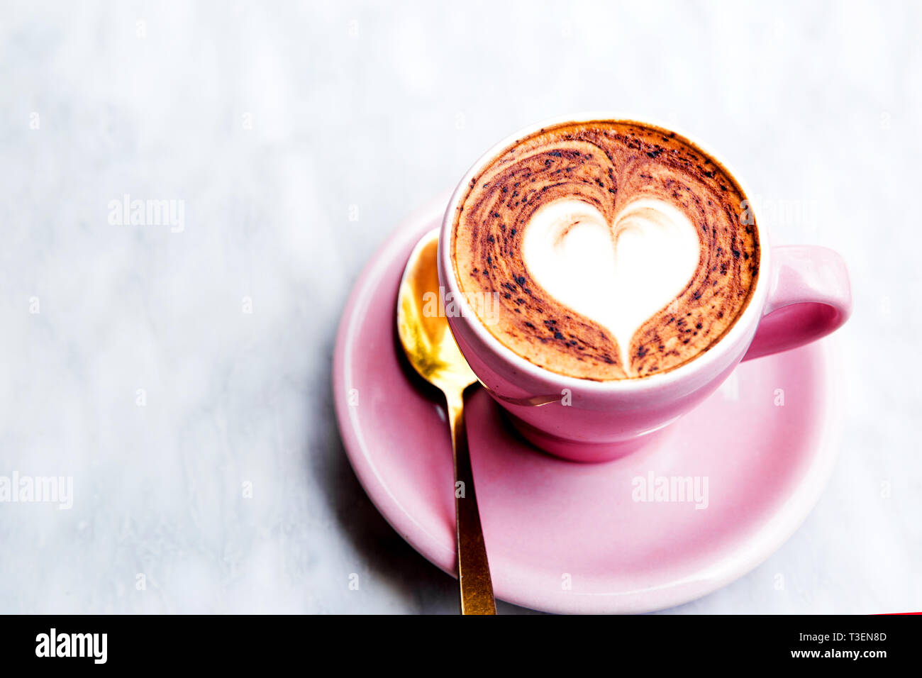 Pastell rosa Cappuccino Tasse mit Herz latte Art Kaffee auf dem Marmor Hintergrund mit ornamentalen Boden Stockfoto