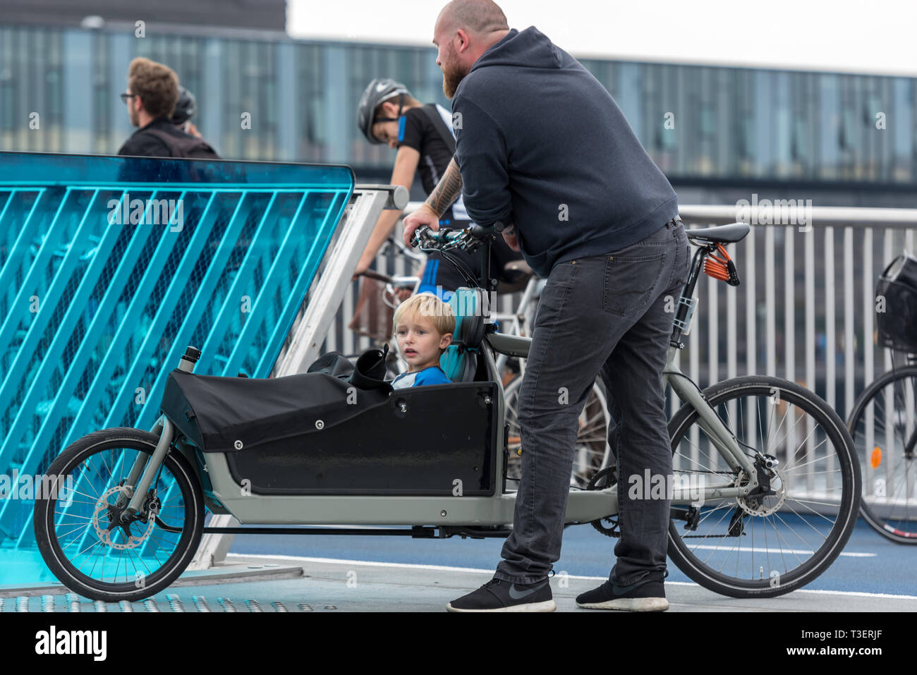 Eine dänische Vater mit seinem kleinen Sohn in einem cargo bike Warten, bis die Inderhavnsbroen (Inner Harbour Bridge) in Kopenhagen zu öffnen. Stockfoto