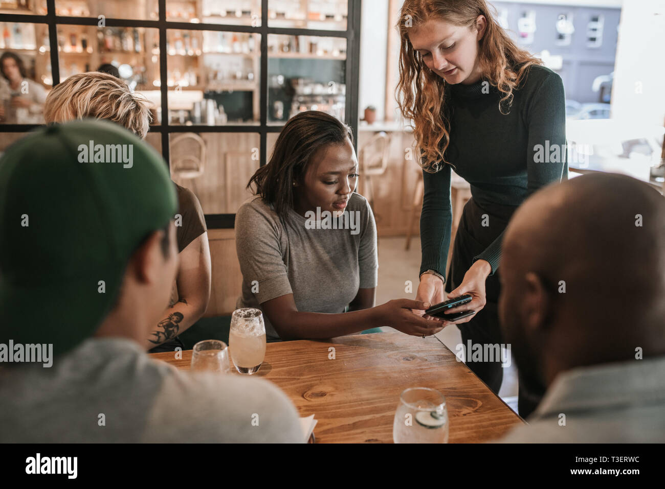 Kunden zahlen einer Restaurantrechnung mit Ihrem Smartphone Stockfoto