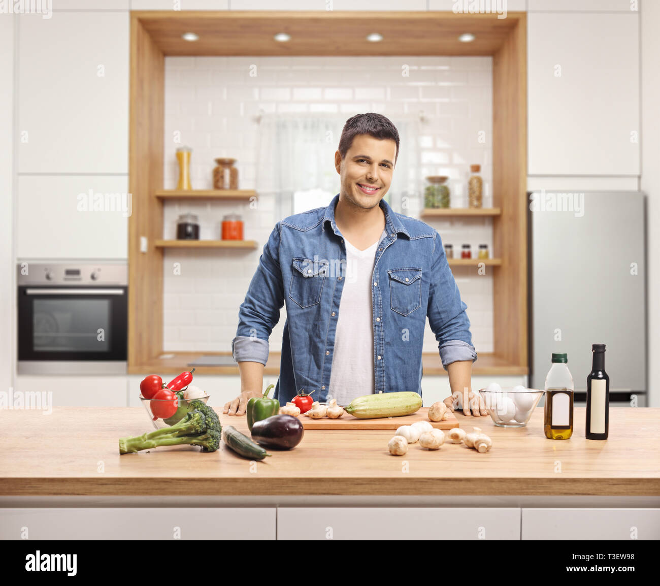 Lächelnden jungen Mann Kochen mit Gemüse in einer Küche Stockfoto