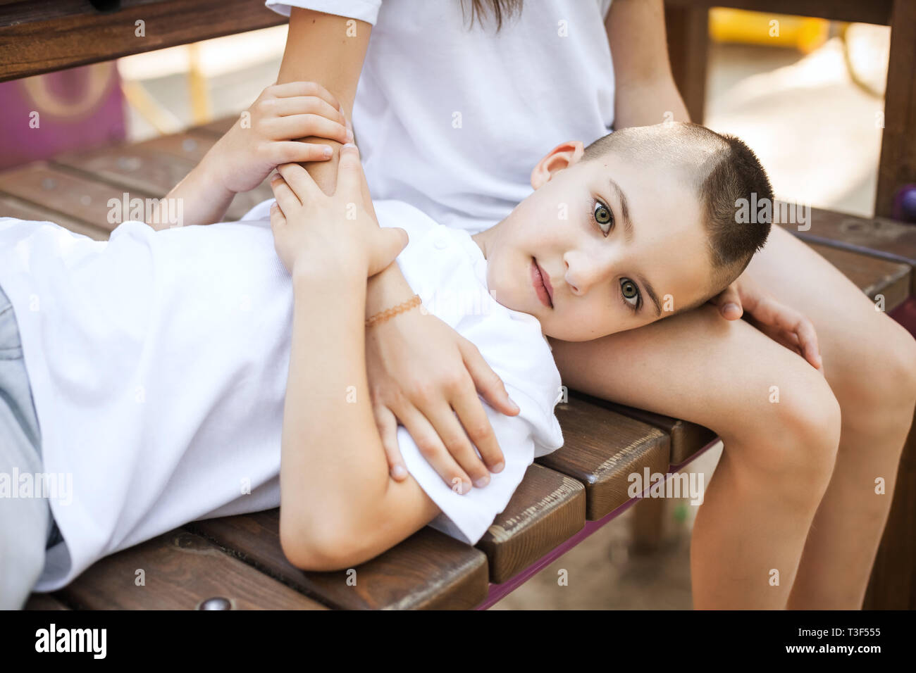 Junge liegend auf Mädchen Beine auf der Bank sitzen Stockfoto
