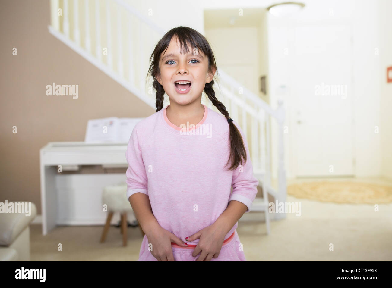6-7 Jahr alt happy Girl mit Blick auf die Kamera zu Hause und lächelnd mit Mund offen. Stockfoto