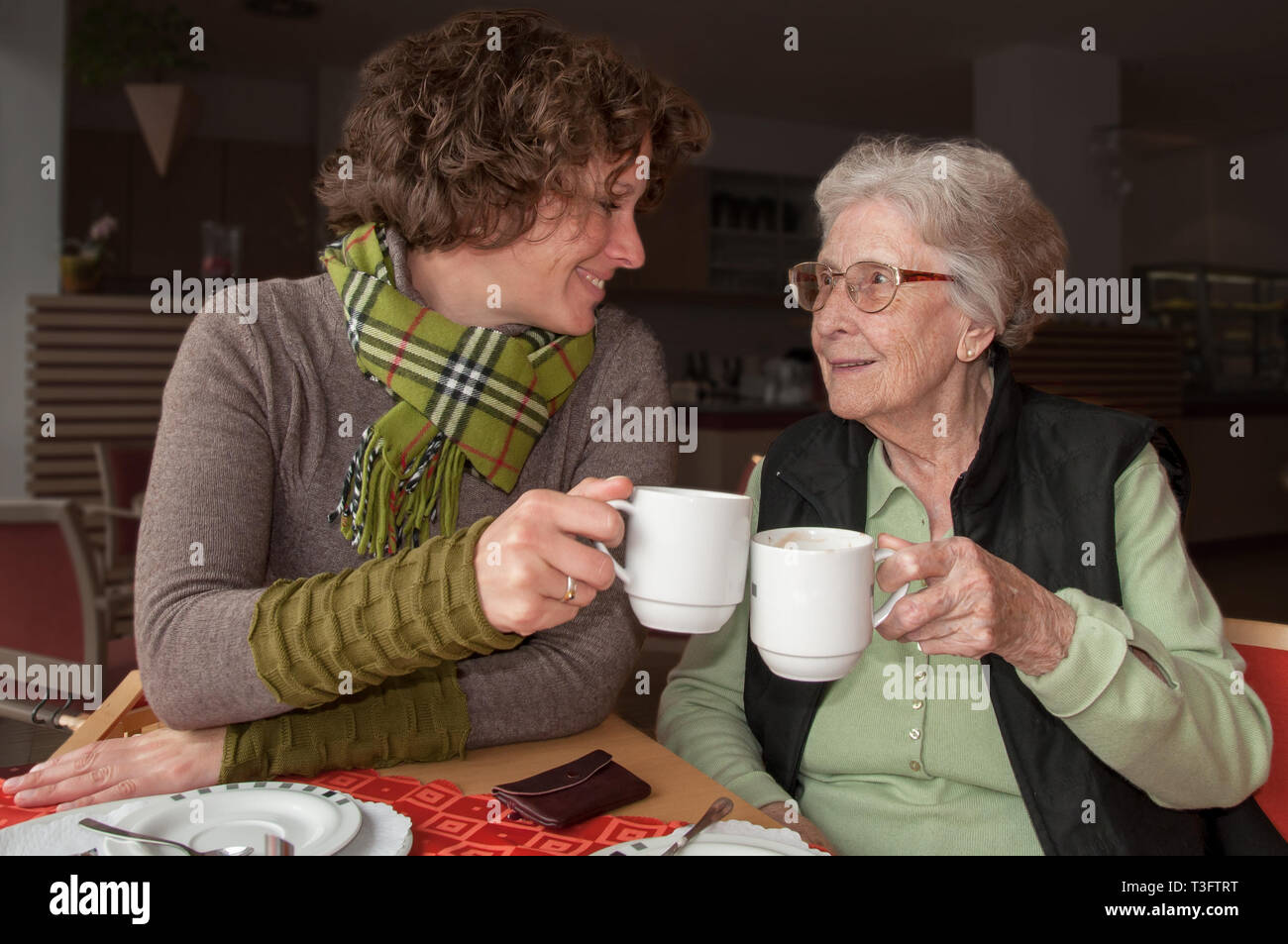 Ältere Frau und Betreuer Toasten mit Kaffee Stockfoto