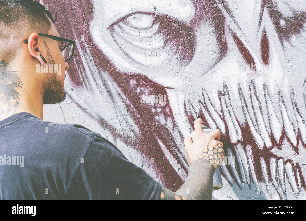 Street Graffiti Künstler Malen mit einem Color Spray einen dunklen Monster Schädel Graffiti an der Wand - Urban Lifestyle, Street Art Konzept Stockfoto