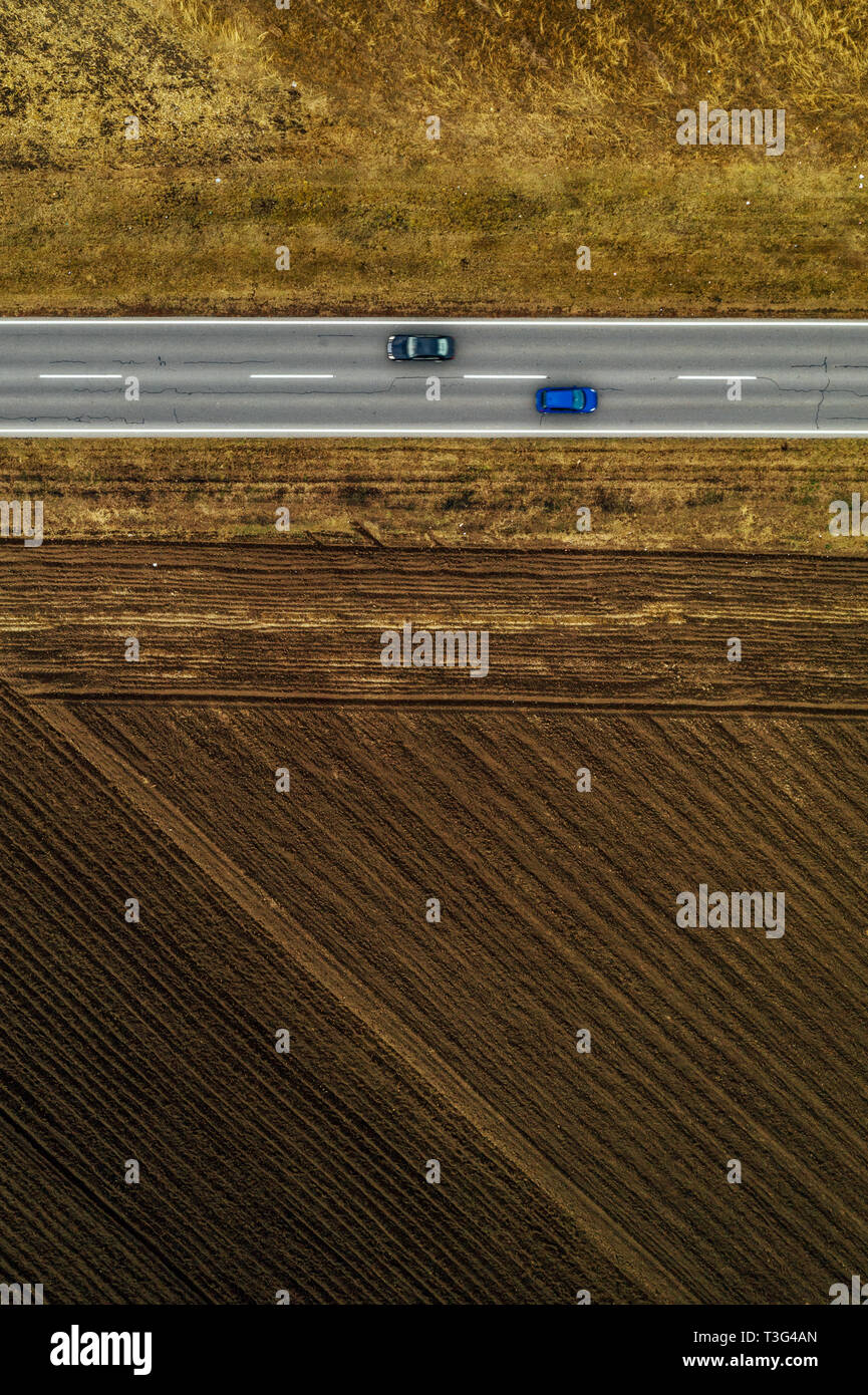 Zwei Autos auf gerader Straße durch die Landschaft im Herbst am Nachmittag, Luftaufnahme von Drone pov Stockfoto