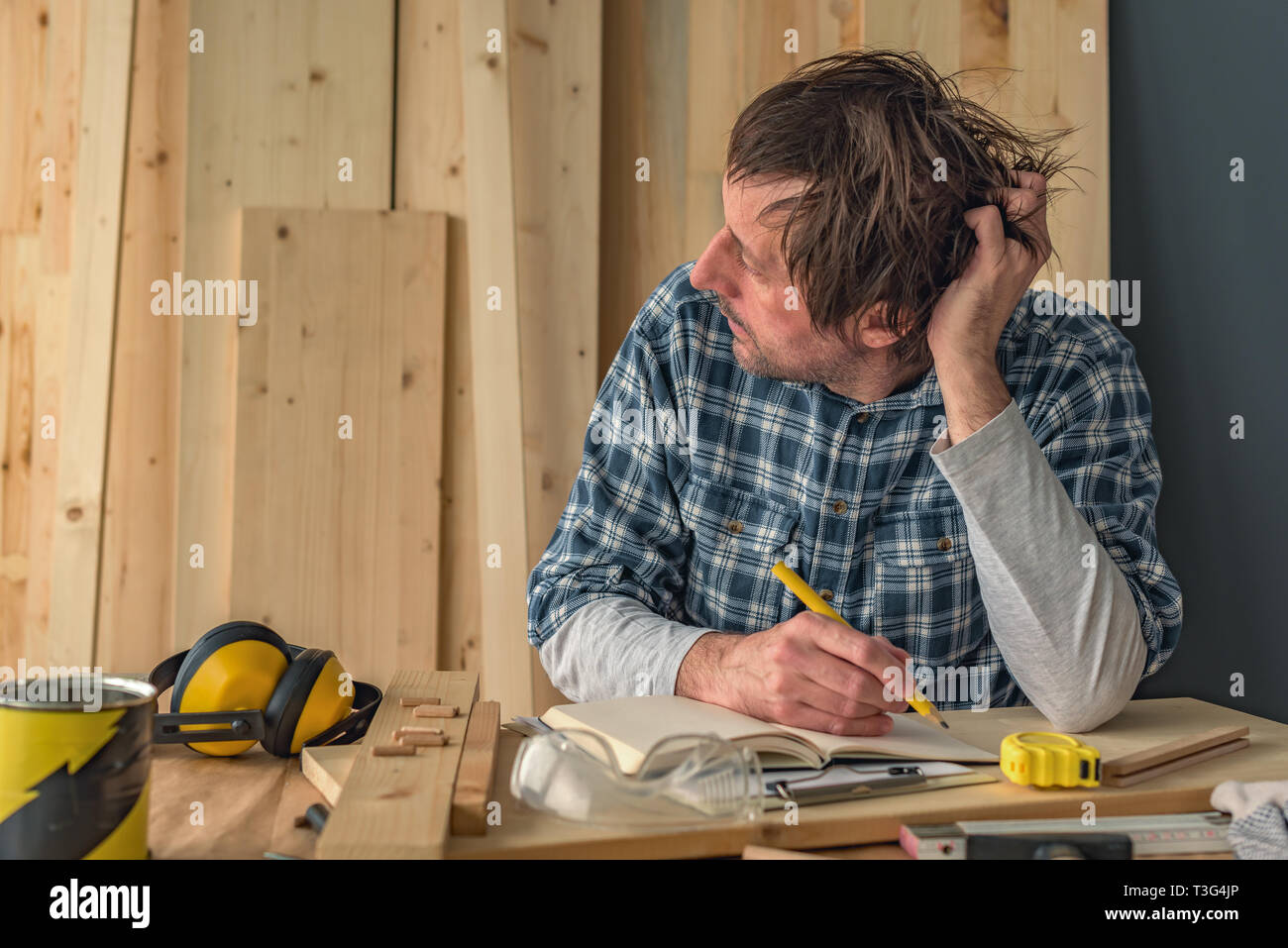 Tischler Denken in Small Business Holzarbeiten workshop Innenraum, nachdenklich nachdenklich männlich ist der Betrachtung und Planung neuer DIY-Projekt Stockfoto
