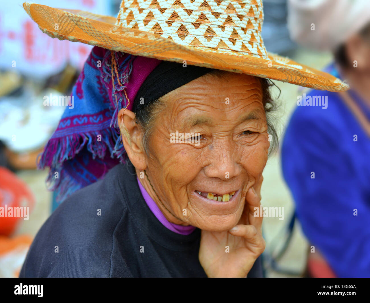 Alte Hani markt Frau (chinesische ethnische Minderheit) mit lebte - Gesicht trägt einen Strohhut über ihre blauen tribal Kopftuch. Stockfoto