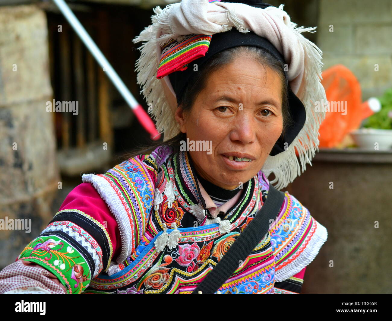 Ältere Miao markt Frau (chinesische ethnische Minderheit) trägt einen farbenfrohen traditionellen ethnischen Kleid und posiert für die Kamera. Stockfoto