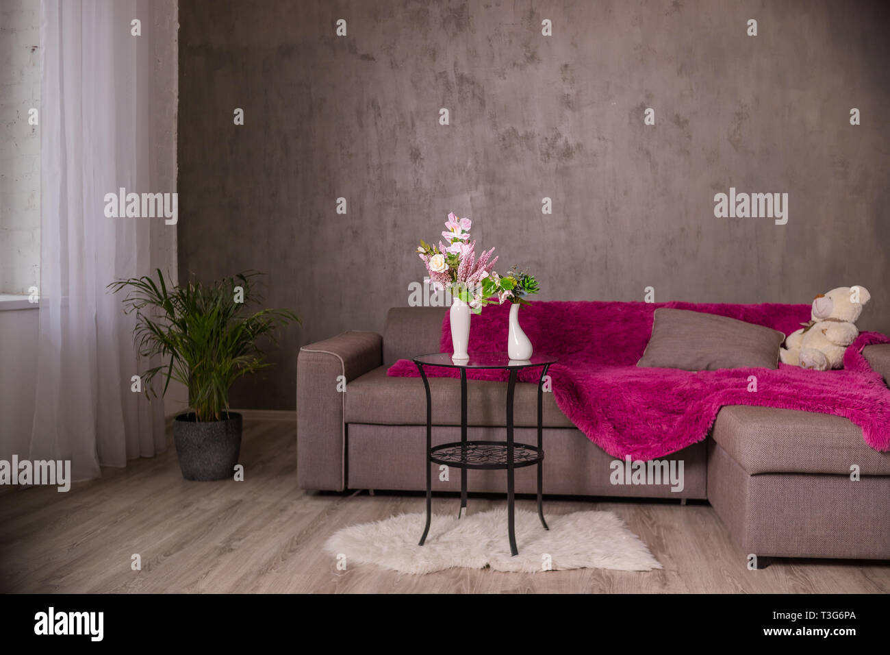 Skandinavische Wohnzimmer Design Interieur Mit Einem Sofa Und Einem Runden Tisch Mit Blumen Blumenstrauss Braun Sofa Mit Plaid Kissen Teddybar Moderne Einrichtung Stockfotografie Alamy