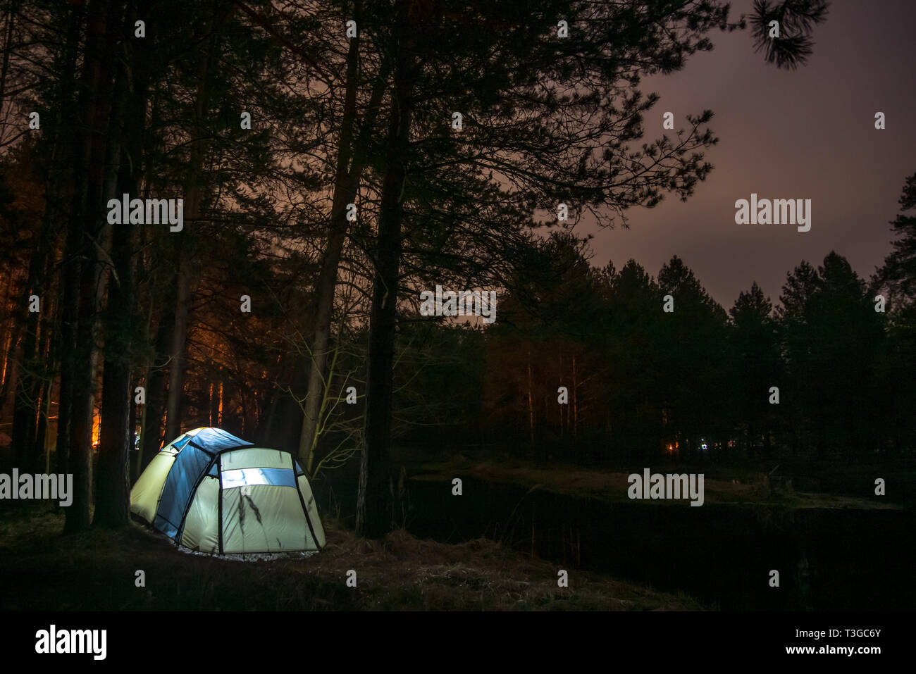 Nacht Landschaft mit beleuchteten Zelt, Wald im Hintergrund. Sommer Camping Stockfoto