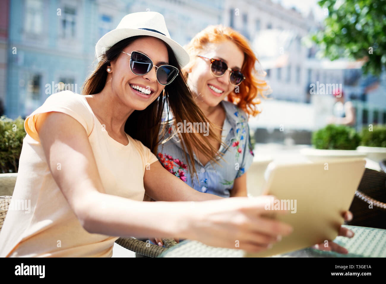 Glückliche junge Frauen mit digitalen Tablette im Cafe im Freien Stockfoto