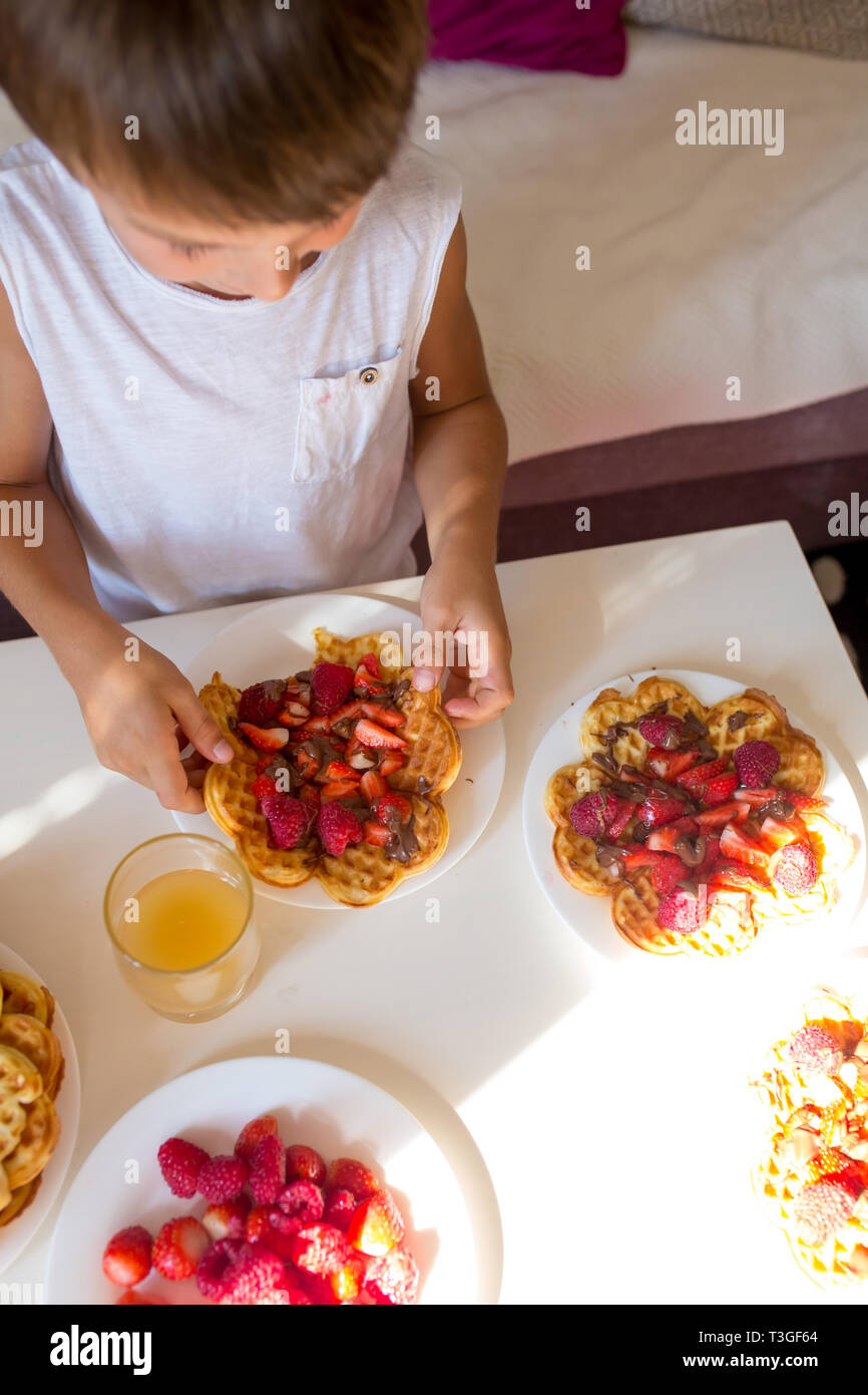 Süßes Geburtstagskind, Essen belgische Waffeln mit Erdbeeren, Himbeeren und Schokolade zu Hause Stockfoto