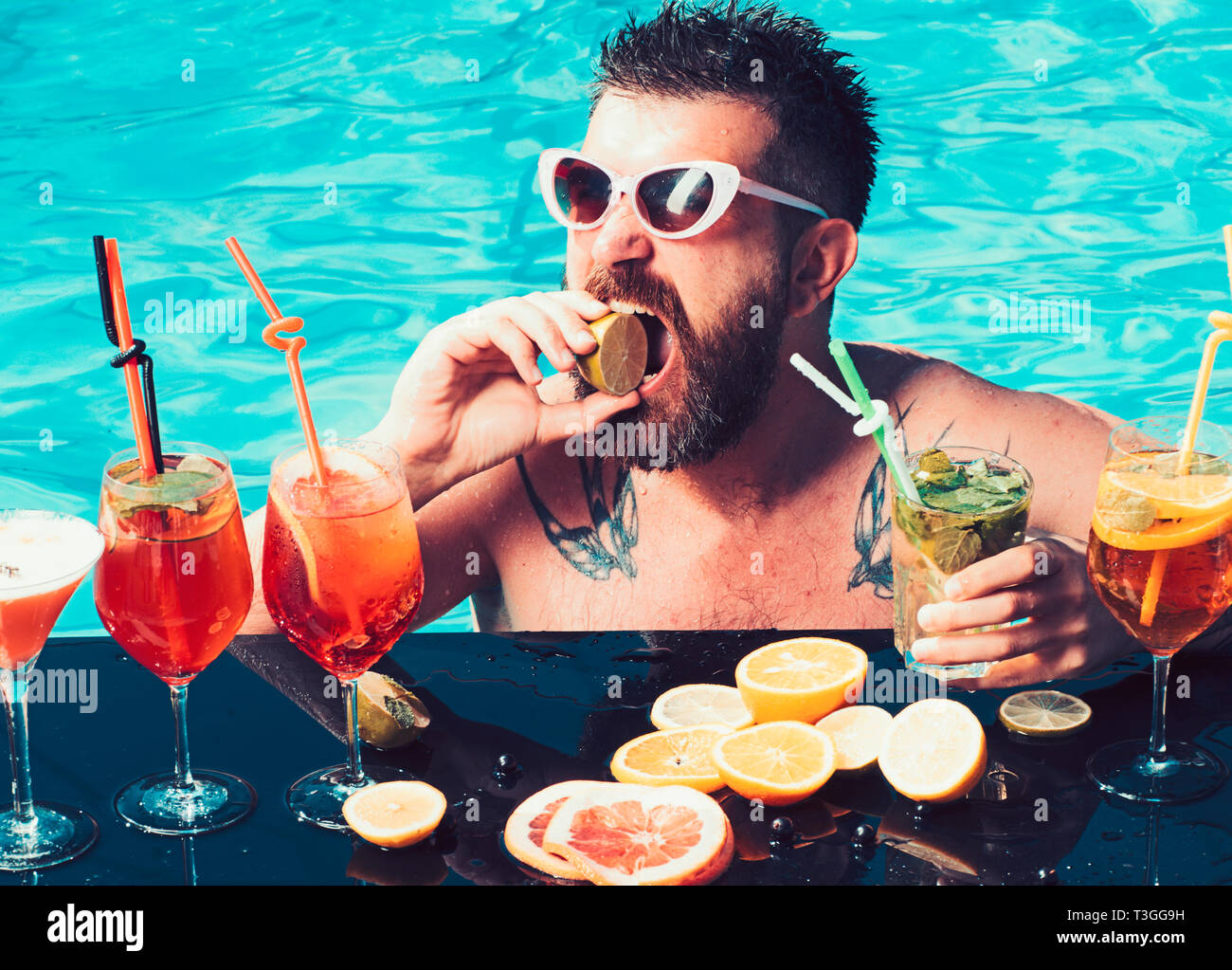 Cocktail mit Obst in der bärtigen Mann im Pool. Mann Schwimmen und trinken Alkohol. Sommer Urlaub in Miami oder Malediven. Pool Party, Vitamin- und Nähren Stockfoto