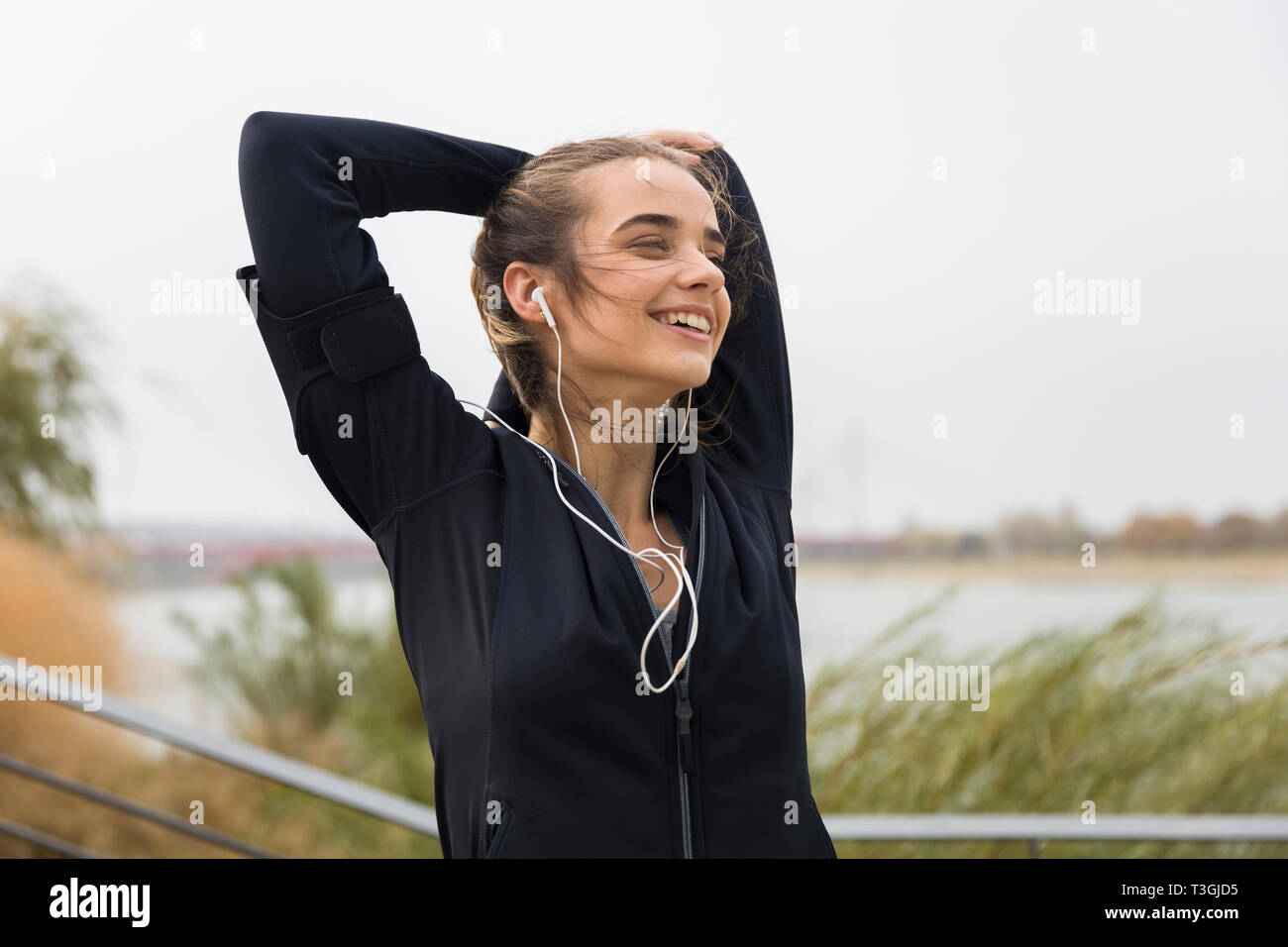Weibliche junge Athlet recken ihre Arme, während Sie Musik hören im Freien Stockfoto