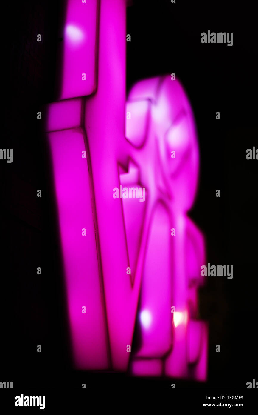 Abstract verschwommen Kunststoff rosa Zeichen des Wortes Liebe auf schwarzem Hintergrund. Trendy 80 s Konzept. Stockfoto