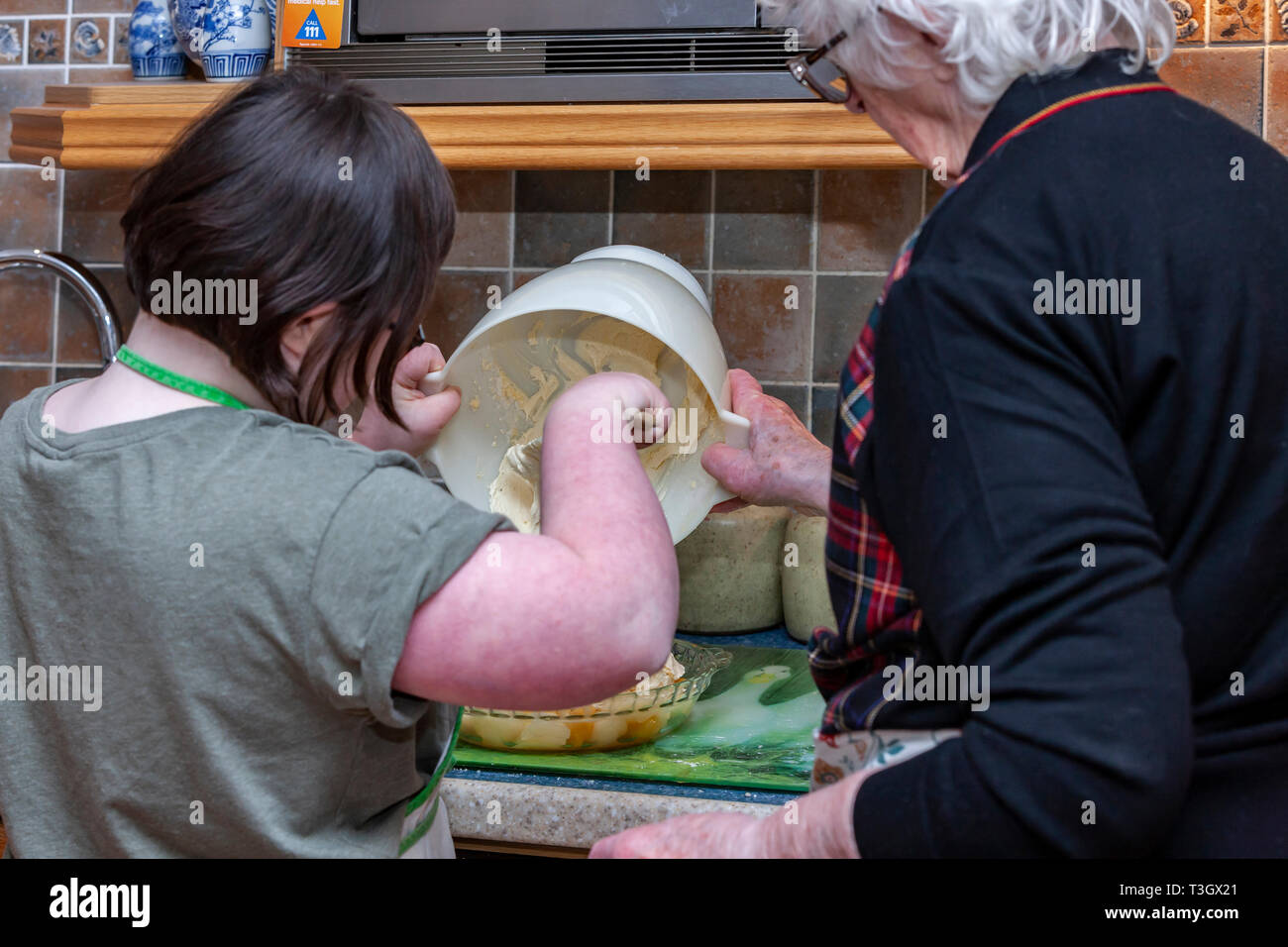 Junges Mädchen mit Down-syndrom lernen Life Skills mit ihrer Großmutter in der Küche. Stockfoto