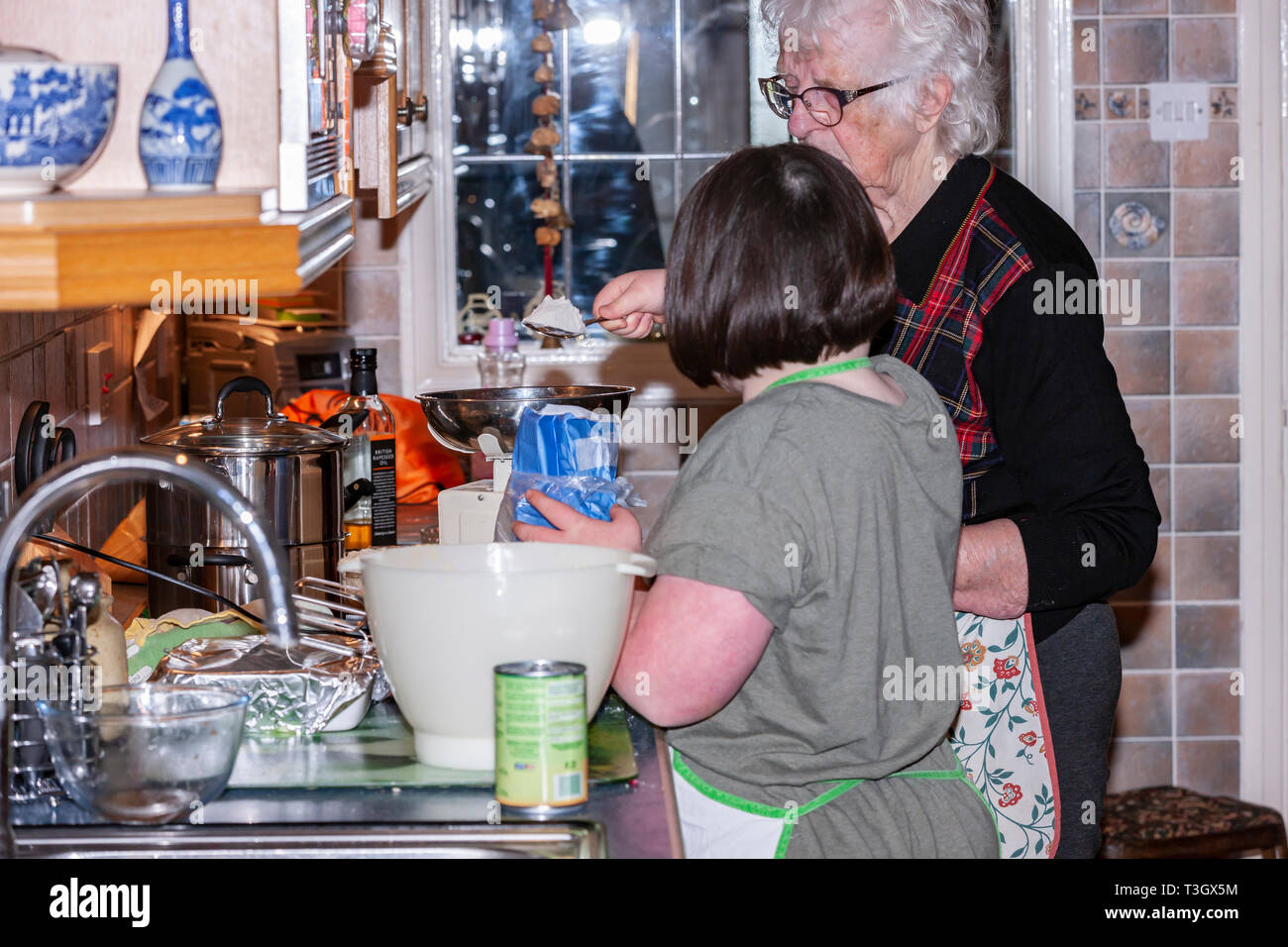 Junges Mädchen mit Down-syndrom lernen Life Skills mit ihrer Großmutter in der Küche. Stockfoto