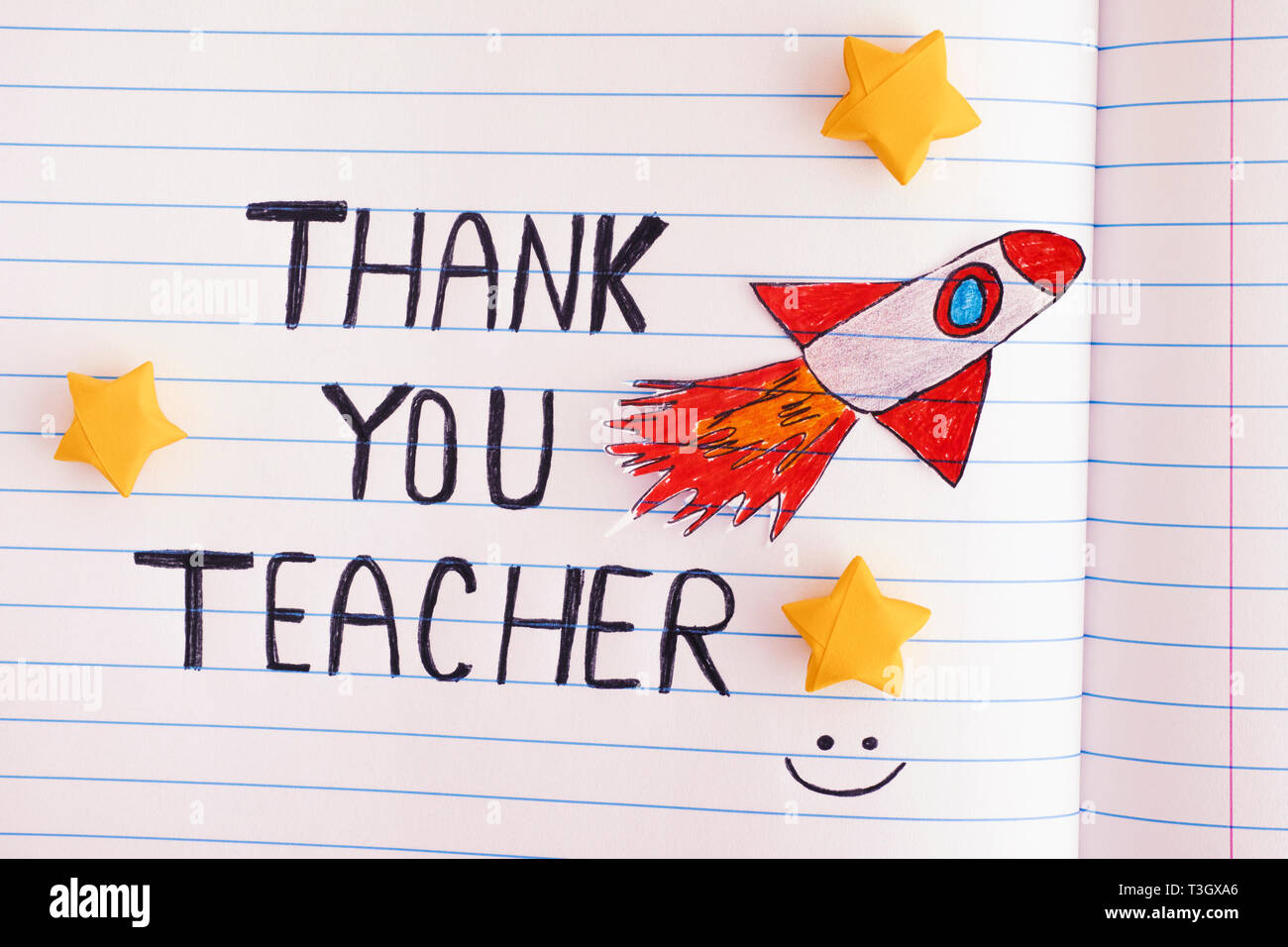 Vielen Dank, dass Sie sich Lehrer. Liniertem Papier notepad mit Worten, vielen Dank, dass Sie sich Lehrer und mit Weltraumrakete Strahlen durch Gelb Origami Sterne. Close Up. Stockfoto
