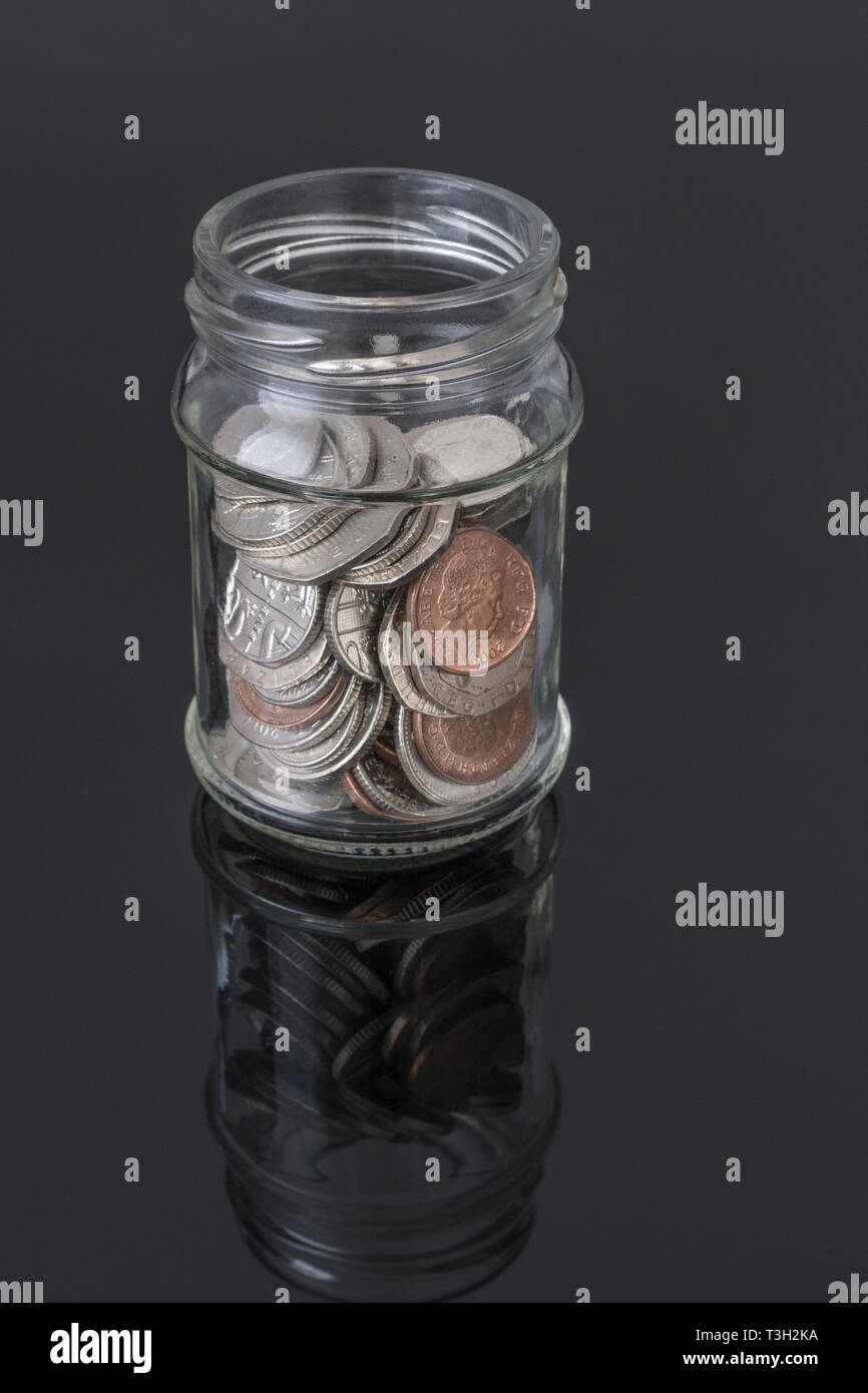 Glas Glas mit UK-Münzen - als Metapher für die persönlichen Ersparnissen, regnerischer Tag sparen, Altersvorsorge Topf, Topf. Stockfoto