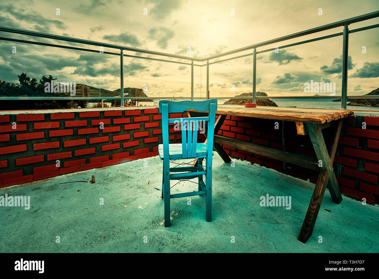 Retro Holz- blauen Stuhl und Tisch auf dem Balkon mit roten Ziegelwänden und eine stimmungsvolle Atmosphäre. Stockfoto