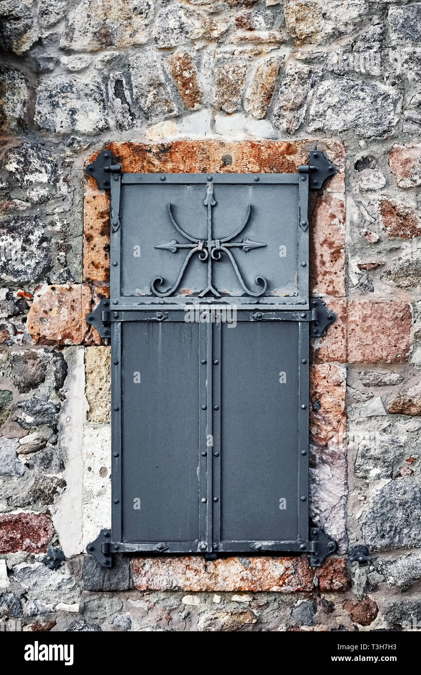 Vintage Fenster mit schwarzem Eisen Shutter und Steinmauer eines antiken Hauses Stockfoto