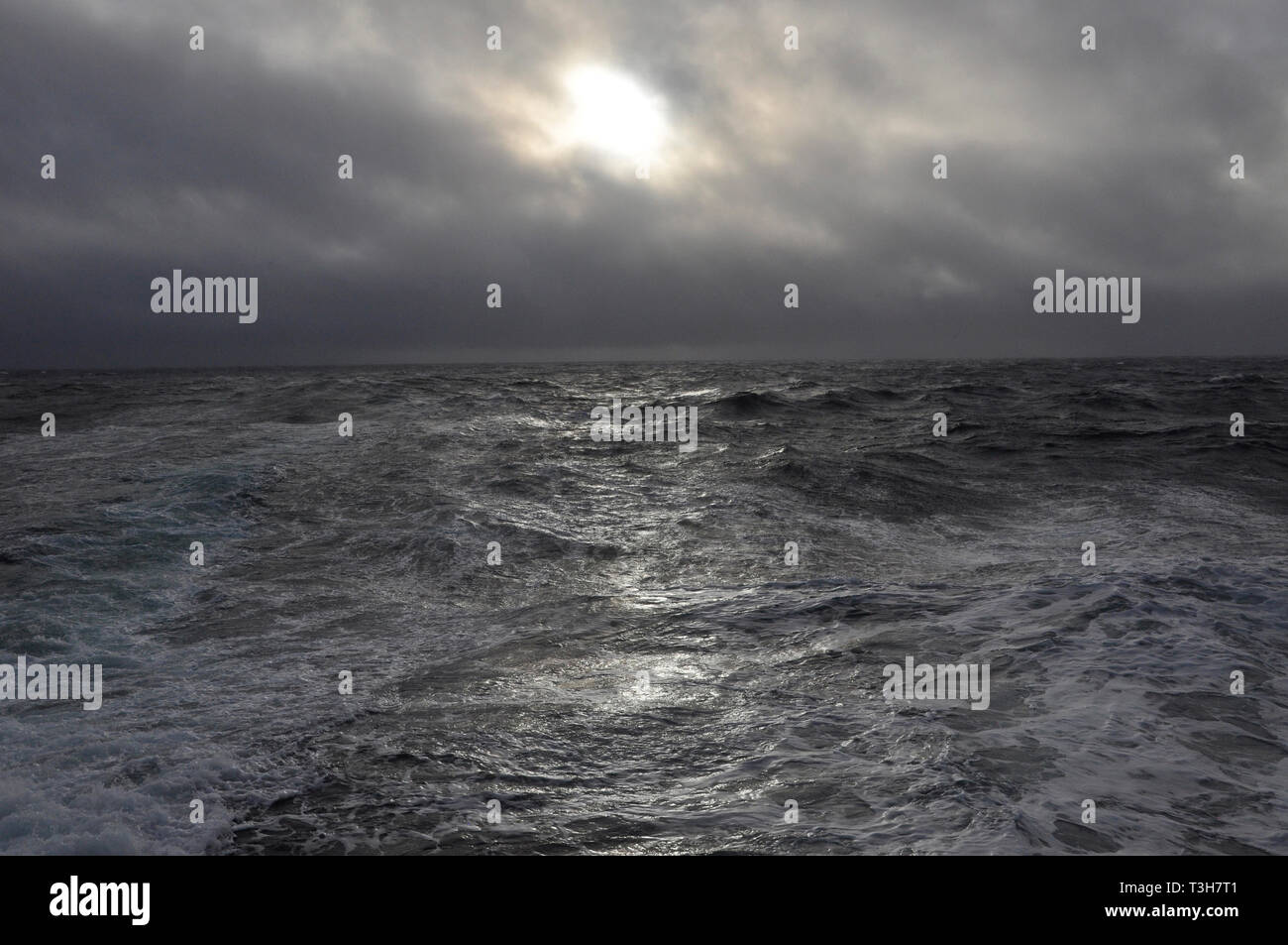 Sonne hinter Wolken über eine dunkle atmosphärische Meer. Aus Cornwall, England, Großbritannien. Stockfoto