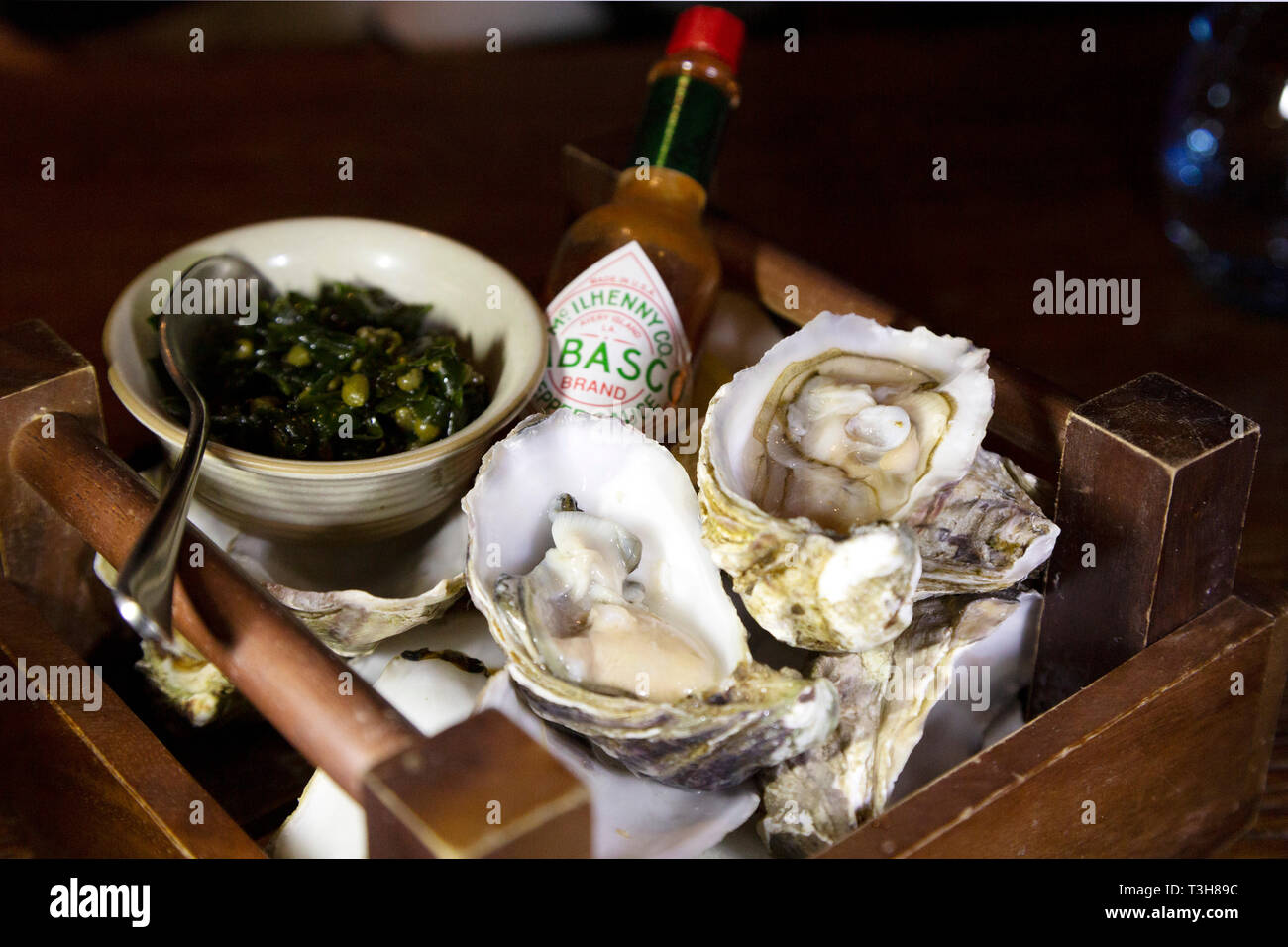Lindisfarne Austern serviert mit einer Mignonette Sauce. Die frischen Austern sind mit Tabasco Sauce vorgestellt. Stockfoto