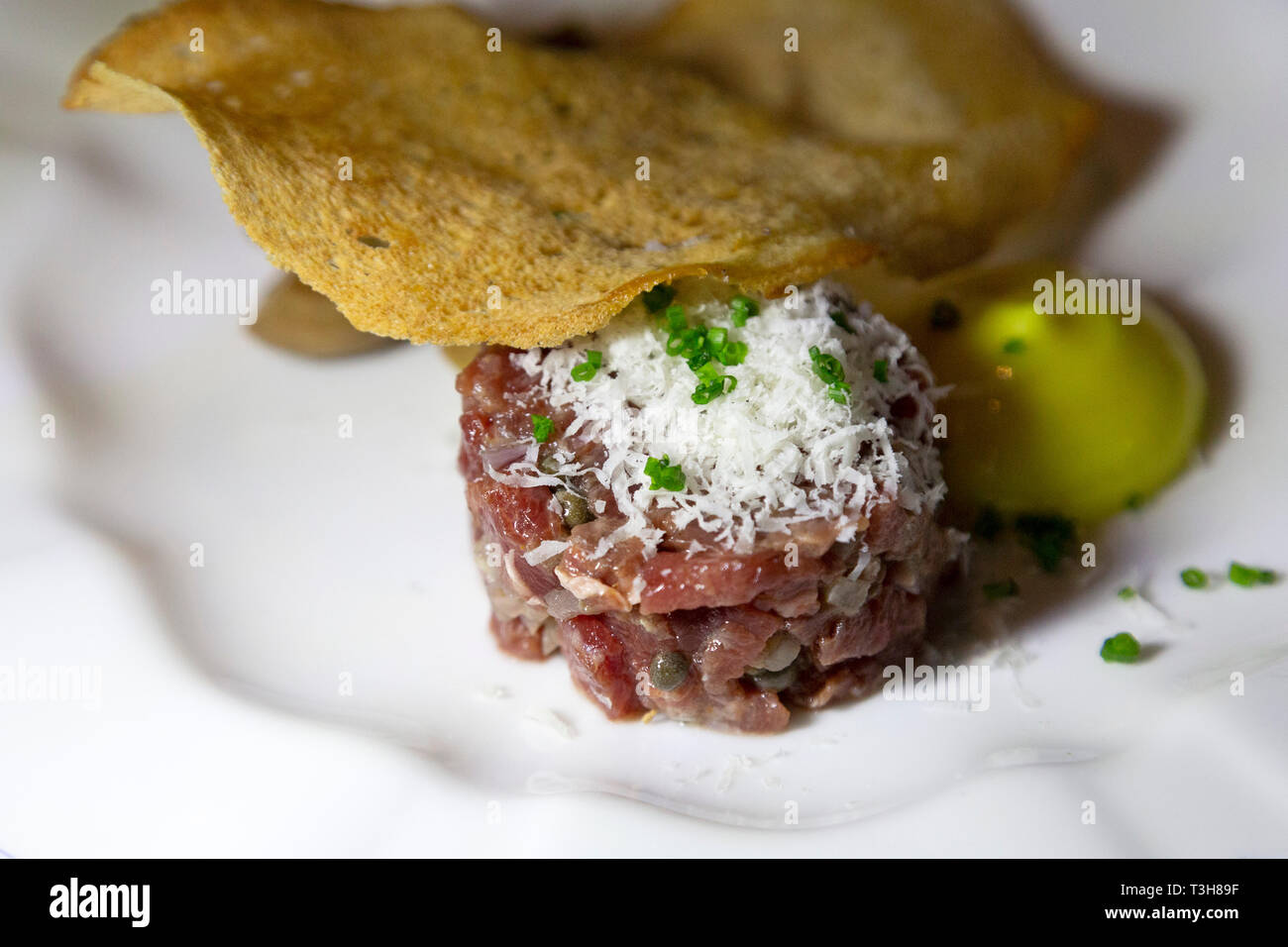 Tatar serviert mit einer dünnen Scheibe Knäckebrot. Die rohen Fleisch ist mit geriebenem Käse gekrönt. Stockfoto