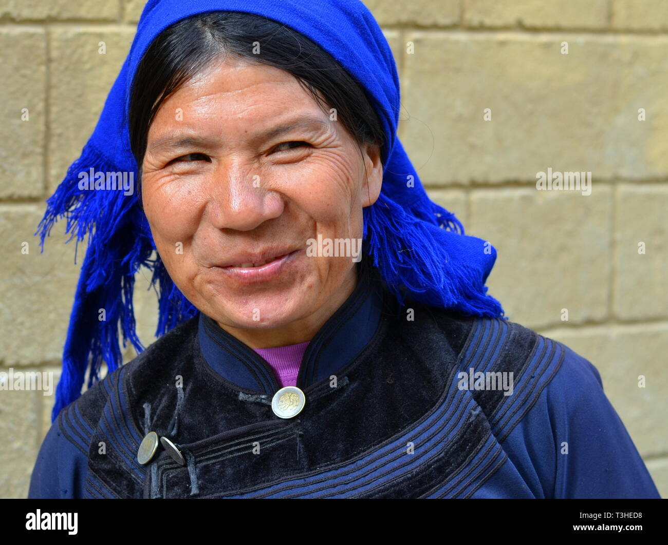 Spitzbübisch - suchen, Reifen Hani Frau (chinesische ethnische Minderheit) trägt eine schwarz-blaue traditionelle ethnische Kostüm mit blauem Kopftuch. Stockfoto